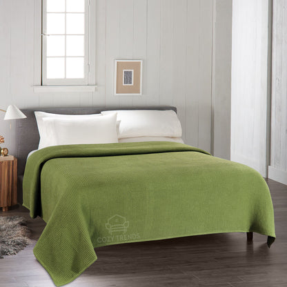Green blanket on a bed in a bedroom with a neutral color scheme