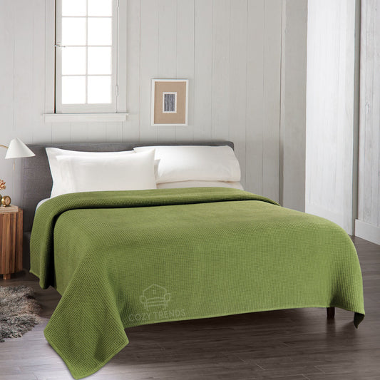 Green blanket on a bed in a bedroom with a neutral color scheme